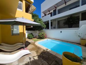 a house with a swimming pool and an umbrella at Terre et Mer - Studios - Ile Maurice in Rivière Noire