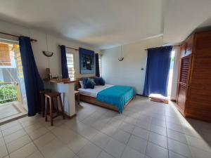 a bedroom with a bed and a kitchen with blue curtains at Terre et Mer - Studios - Ile Maurice in Rivière Noire +51 photos
