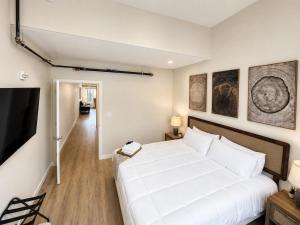 a bedroom with a large white bed and a television at The Accessible Atom | Historic Main in St. Charles