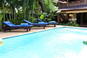 a swimming pool with blue lounge chairs next to a house at Lovina Beachhouse Villas in Lovina