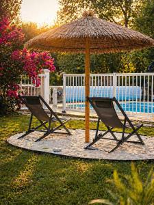 a pair of chairs under an umbrella and a bench at La biche au bois piscine chauffee jacuzzi in Cazals