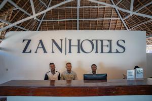 a group of men standing in front of a company sign at ZAN Island Beach in Jambiani