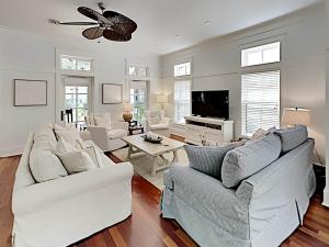 a living room with white furniture and a flat screen tv at Watercolor Whimsea in Seagrove Beach