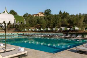 a large swimming pool with lounge chairs and umbrellas at Chapter Chianti, a Member of Design Hotels in Cavriglia