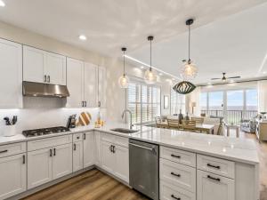 a kitchen with white cabinets and a dining room at Adagio #401B in Santa Rosa Beach