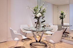 a table with white chairs and a vase of flowers at No.5 Maddox Street in London