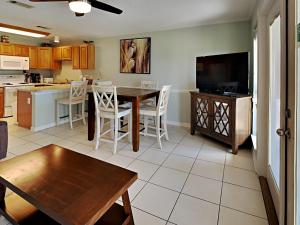 a kitchen and dining room with a table and a tv at Grand Caribbean Perdido Key #114 West in Perdido Key