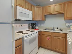 a kitchen with white appliances and wooden cabinets at Grand Caribbean Perdido Key #114 West in Perdido Key +12 photos