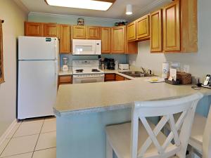 a kitchen with a white refrigerator and wooden cabinets at Grand Caribbean Perdido Key #114 West in Perdido Key