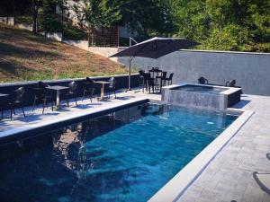 a pool with a table and chairs and an umbrella at Kuća za odmor Đogić - bazen & jacuzzi in Ilidža