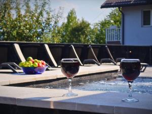two glasses of wine sitting on a table next to a swimming pool at Kuća za odmor Đogić - bazen & jacuzzi in Ilidža