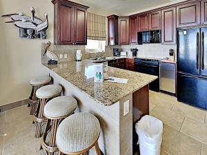 a kitchen with a island with bar stools at Beach Club #206A in Pensacola Beach +9 photos
