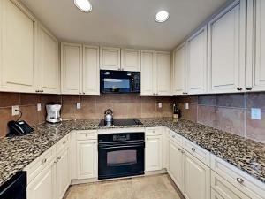 a kitchen with white cabinets and a stove top oven at Portofino Island Resort #2-1608 in Pensacola Beach +21 photos