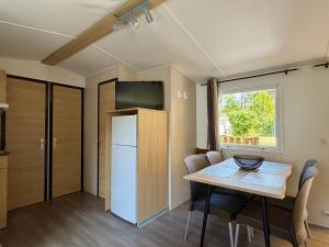 a small kitchen with a table and a refrigerator at Évasion famille - Dune Blanche in Camiers