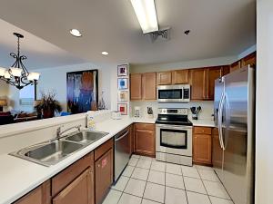 a kitchen with wooden cabinets and stainless steel appliances at Emerald Dolphin #1630 in Pensacola Beach