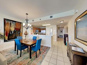 a dining room and kitchen with a table and blue chairs at Emerald Dolphin #1630 in Pensacola Beach