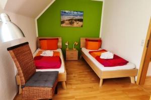 a small room with two beds and a chair at Haus Rüther in Borkum