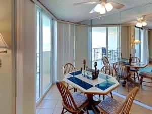 a dining room with a table and chairs and windows at Santa Rosa Dunes #952 in Pensacola Beach