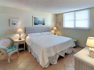 a bedroom with a large white bed and two chairs at Santa Rosa Dunes #952 in Pensacola Beach