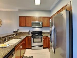 a kitchen with wooden cabinets and a stainless steel refrigerator at Village Of South Walton #263A in Rosemary Beach +18 photos