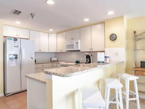a kitchen with white cabinets and a white refrigerator at Emerald Isle #401 in Pensacola Beach +18 photos