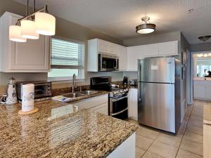 a kitchen with white cabinets and a stainless steel refrigerator at Gulf Island #621 in Navarre