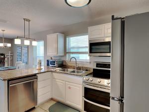 a kitchen with white cabinets and a stainless steel refrigerator at Gulf Island #621 in Navarre +13 photos