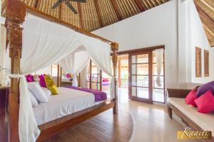 a bedroom with a canopy bed with colorful pillows at Villa Kaaiti in Uluwatu