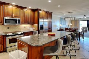 a kitchen with wooden cabinets and a island with bar chairs at Aegean #332 in Destin