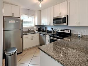 a kitchen with white cabinets and a stainless steel refrigerator at Beachside Villas #413 in Seagrove Beach