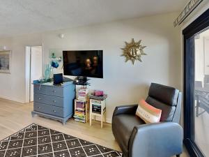 a living room with a chair and a tv at Ocean Breeze East #303 in Perdido Key
