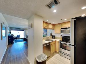 a kitchen with wooden cabinets and a black refrigerator at Ocean Breeze East #303 in Perdido Key +21 photos