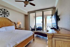 a bedroom with a bed and a desk with a television at Beach Club #1804C in Pensacola Beach