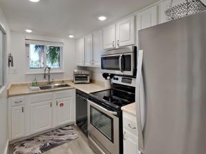a kitchen with white cabinets and a stainless steel refrigerator at Driftwood Towers #1F - Palm View in Gulf Shores +26 photos