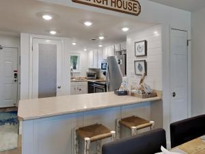 a kitchen with white cabinets and a counter with stools at Driftwood Towers #1F - Palm View in Gulf Shores