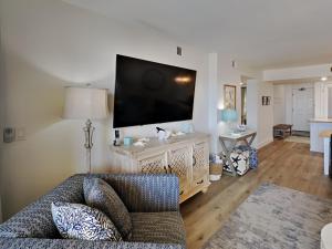 a living room with a couch and a flat screen tv at Driftwood Towers #1F - Palm View in Gulf Shores