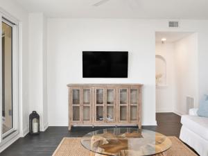a living room with a tv on a white wall at Beach Colony Towers #2B - Villa Monarch in Perdido Key