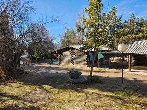 a log cabin with a tree and a rock at Cabañas San Francisco in Potrerillos