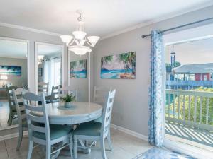 a dining room with a table and chairs and a balcony at Villas on the Gulf #E7 - Flip Flop Inn in Pensacola Beach
