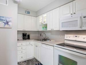 a white kitchen with white cabinets and a sink at Villas on the Gulf #E7 - Flip Flop Inn in Pensacola Beach +27 photos