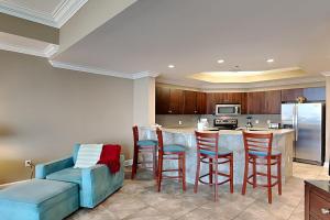 a kitchen with a bar with chairs and a couch at Phoenix West II #1407 in Orange Beach