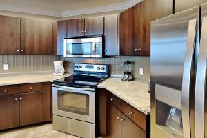 a kitchen with stainless steel appliances and wooden cabinets at Phoenix West II #1407 in Orange Beach