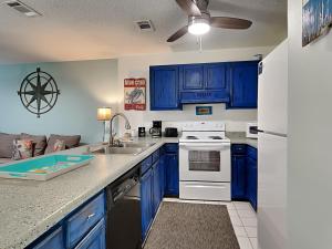 a kitchen with blue cabinets and a white stove top oven at Island Home 102 in Destin