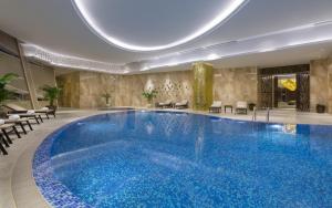 a large swimming pool in a hotel lobby with chairs at Hilton Astana in Astana