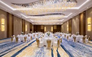 a ballroom with white tables and chairs and a chandelier at Hilton Astana in Astana +96 photos