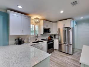 a kitchen with white cabinets and a stainless steel refrigerator at Beachside Villas 911 in Seagrove Beach