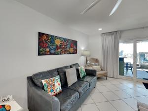 a living room with a black leather couch in a room at Tiki Tango Hideaway in Panama City Beach
