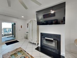 a living room with a fireplace and a flat screen tv at Tiki Tango Hideaway in Panama City Beach +35 photos