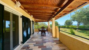 a porch with a wooden roof with a table on it at TETRAKTYS ESTATE beachside seaview ΥΔΩΡ with big garden in Halikounas