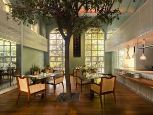 a dining room with a tree and a table and chairs at Raffles Sentosa Singapore in Singapore